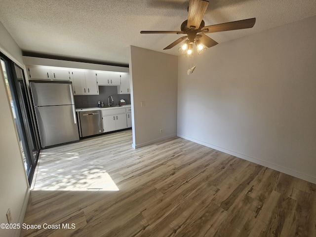 interior space with light wood-style floors, a textured ceiling, baseboards, and a sink