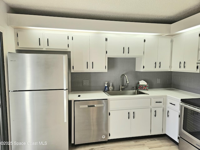 kitchen featuring decorative backsplash, stainless steel appliances, light countertops, light wood-type flooring, and a sink