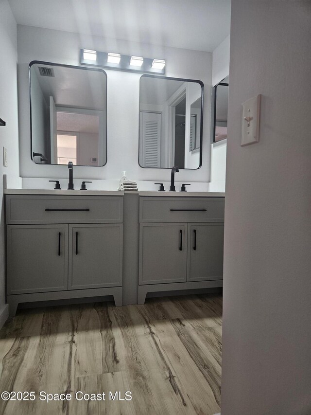 bathroom featuring double vanity, a sink, and wood finished floors