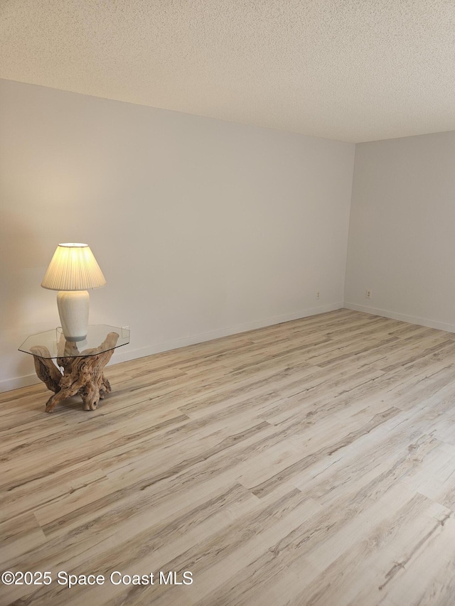 unfurnished room featuring a textured ceiling, baseboards, and wood finished floors