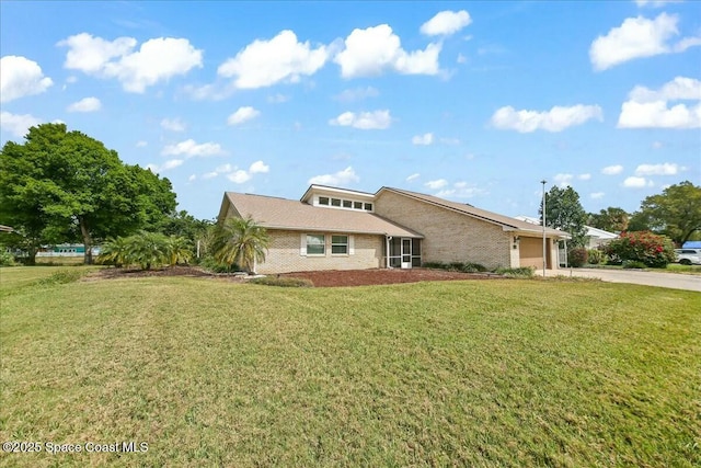 view of front of home featuring concrete driveway, a front lawn, an attached garage, and brick siding