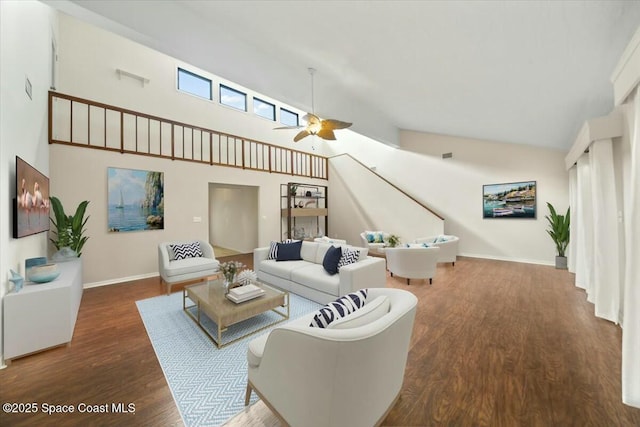 living room with a ceiling fan, wood finished floors, a towering ceiling, and baseboards