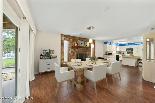 dining space featuring dark wood-style flooring, visible vents, and a fireplace