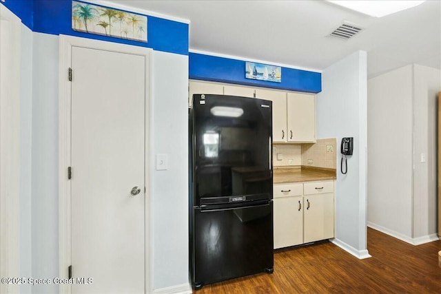 kitchen featuring dark wood-style flooring, light countertops, backsplash, freestanding refrigerator, and white cabinets