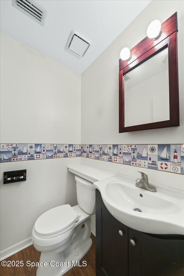 bathroom featuring baseboards, visible vents, toilet, wood finished floors, and vanity