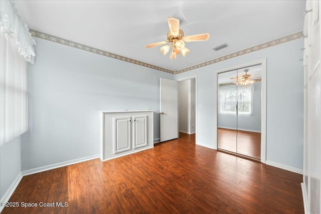 unfurnished bedroom featuring a closet, wood finished floors, visible vents, and baseboards