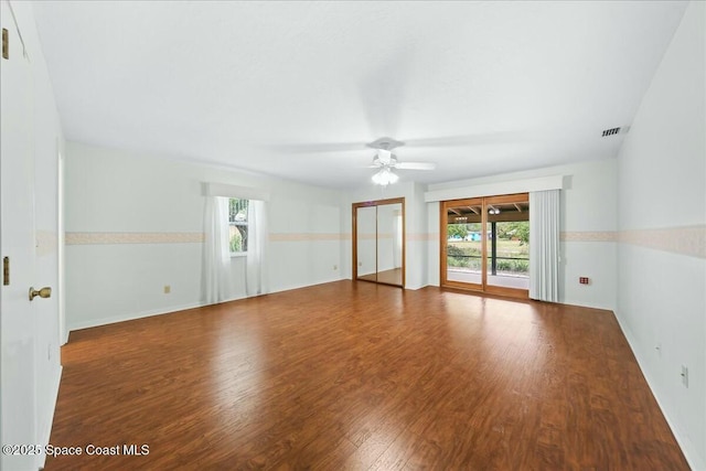 empty room with a healthy amount of sunlight, visible vents, a ceiling fan, and wood finished floors