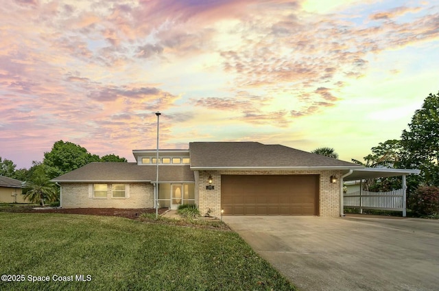 view of front of home featuring driveway, brick siding, a garage, and a front yard