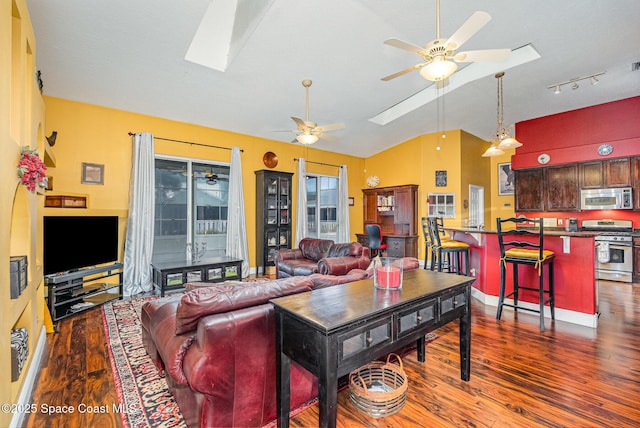 living area with lofted ceiling with skylight, baseboards, a ceiling fan, and wood finished floors