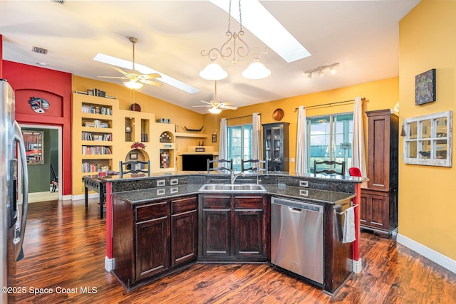 kitchen featuring vaulted ceiling with skylight, visible vents, appliances with stainless steel finishes, dark wood-type flooring, and a sink