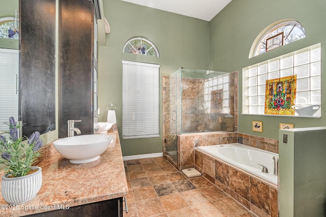 bathroom featuring a towering ceiling, a stall shower, vanity, baseboards, and a bath