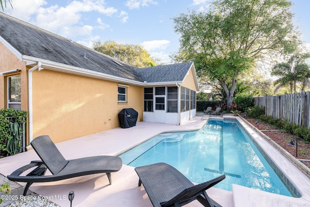 view of swimming pool with a sunroom, a patio area, a fenced backyard, and a fenced in pool