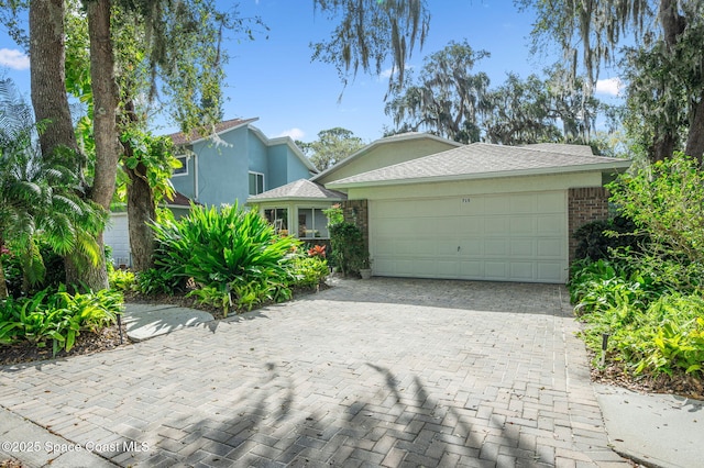 view of front of home with an attached garage, stucco siding, decorative driveway, and brick siding