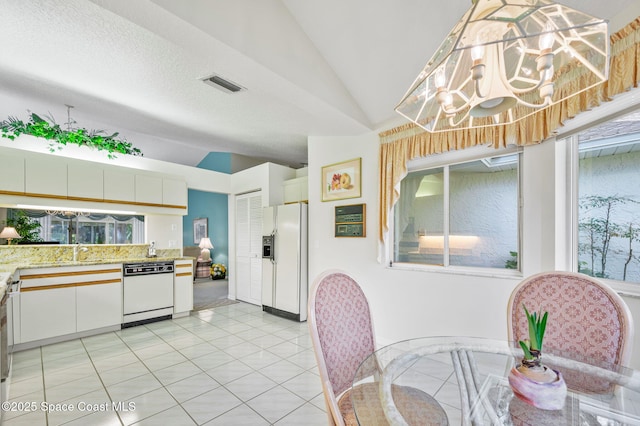 kitchen with light tile patterned floors, white appliances, visible vents, white cabinetry, and vaulted ceiling