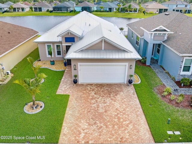 view of front of home with metal roof, an attached garage, decorative driveway, a residential view, and a standing seam roof