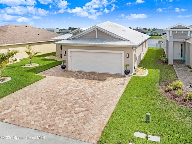 view of front of property with metal roof, decorative driveway, a front yard, and stucco siding