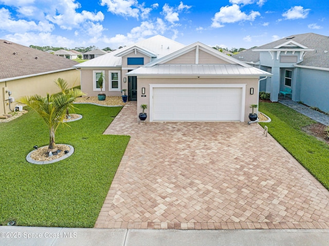 single story home featuring metal roof, an attached garage, decorative driveway, stucco siding, and a front lawn