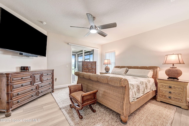 bedroom featuring a textured ceiling, ceiling fan, light wood-style flooring, baseboards, and access to outside