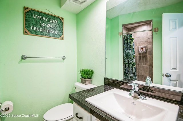 bathroom with toilet, visible vents, a tile shower, and vanity