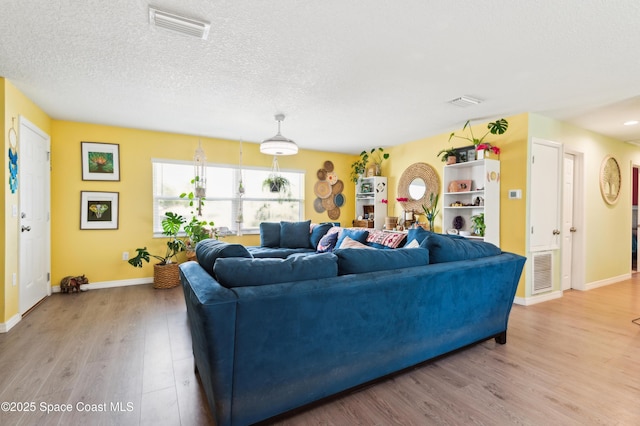 living room with a textured ceiling, wood finished floors, and visible vents