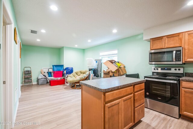 kitchen featuring light wood-type flooring, dark countertops, visible vents, and stainless steel appliances