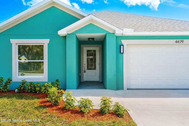 view of exterior entry featuring an attached garage, a shingled roof, and stucco siding