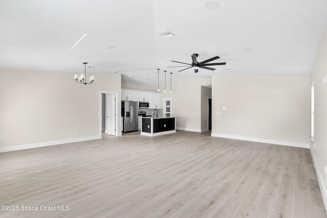 unfurnished living room with ceiling fan with notable chandelier, light wood-style flooring, lofted ceiling, and visible vents