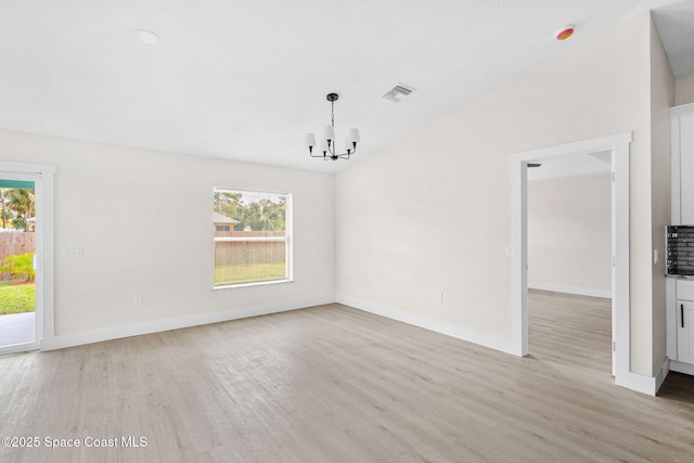 empty room featuring baseboards, light wood finished floors, visible vents, and an inviting chandelier