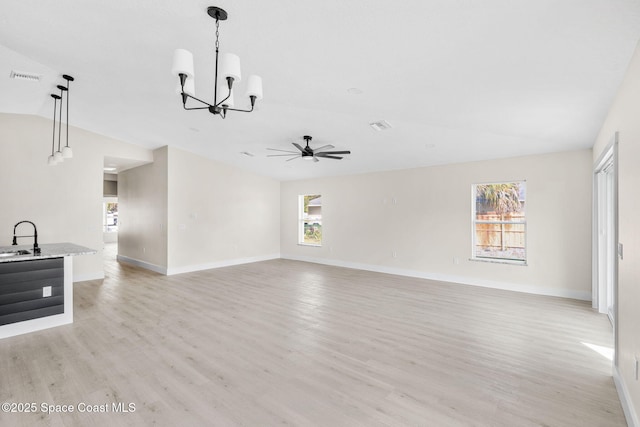 unfurnished living room with lofted ceiling, light wood finished floors, visible vents, and baseboards