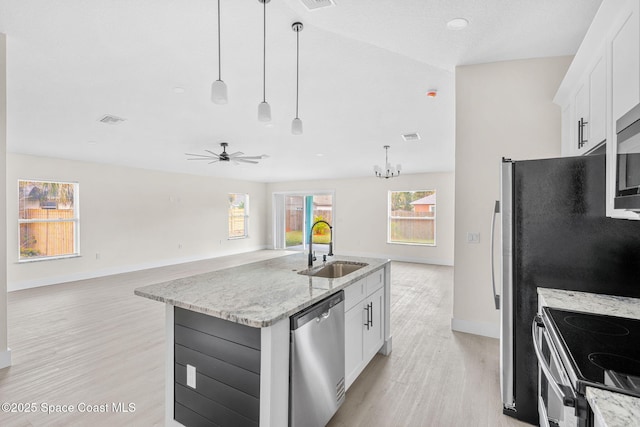 kitchen with a sink, visible vents, open floor plan, appliances with stainless steel finishes, and decorative light fixtures