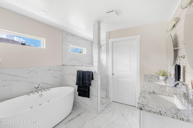 full bath with a soaking tub, marble finish floor, a sink, and a textured ceiling