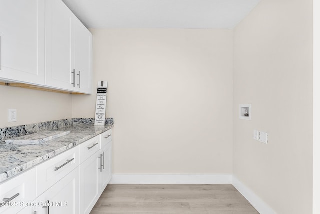 clothes washing area with washer hookup, baseboards, cabinet space, and light wood finished floors