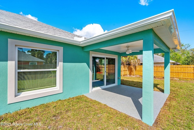 property entrance featuring a patio, stucco siding, a lawn, a ceiling fan, and fence