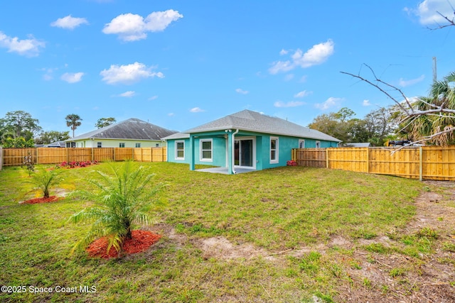 rear view of property with stucco siding, a fenced backyard, and a yard