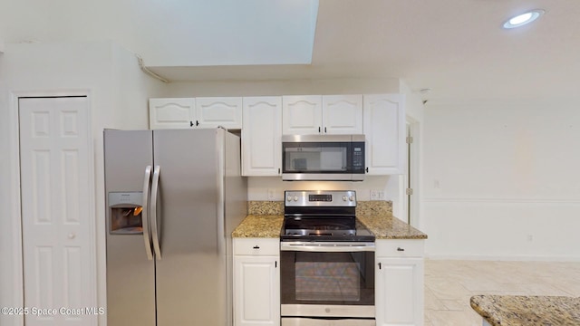 kitchen with appliances with stainless steel finishes, white cabinetry, and light stone counters