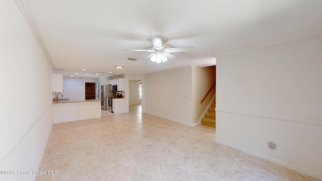 unfurnished living room with ornamental molding, a sink, ceiling fan, and stairs