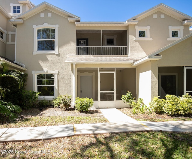 multi unit property with a balcony, a sunroom, and stucco siding