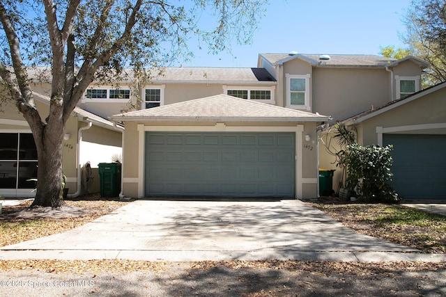 view of front of house with roof with shingles, an attached garage, and stucco siding