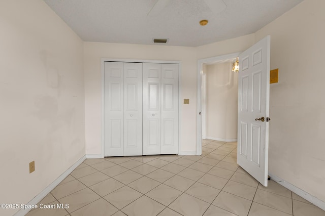 unfurnished bedroom with light tile patterned floors, a closet, visible vents, and baseboards