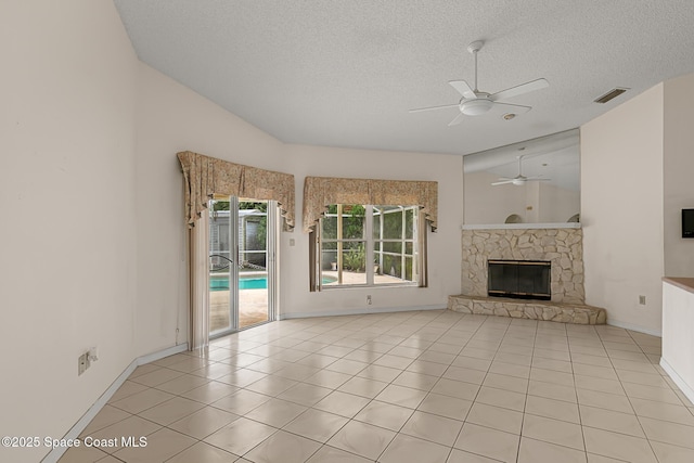 unfurnished living room featuring light tile patterned floors, a textured ceiling, a fireplace, visible vents, and a ceiling fan