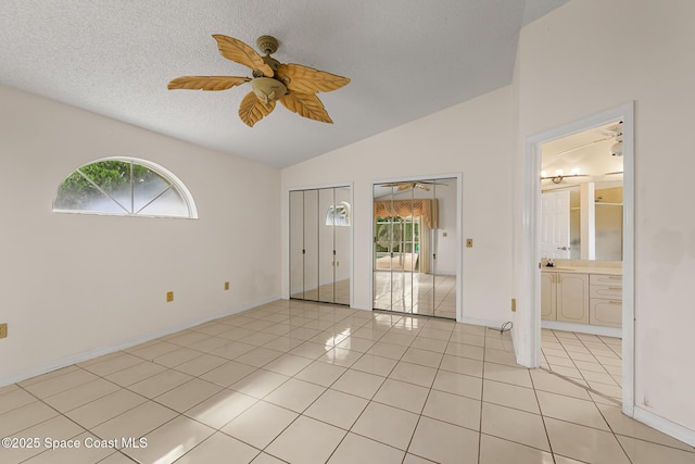 unfurnished room featuring light tile patterned floors, ceiling fan, vaulted ceiling, and a wealth of natural light