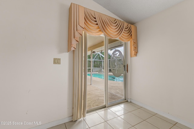 doorway featuring a textured ceiling, light tile patterned flooring, and baseboards