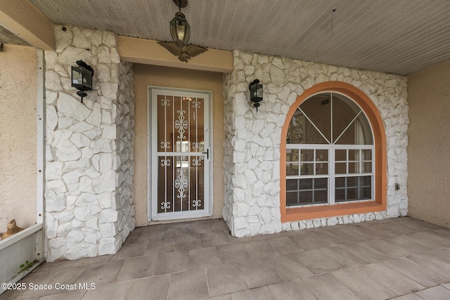 property entrance featuring stone siding and stucco siding