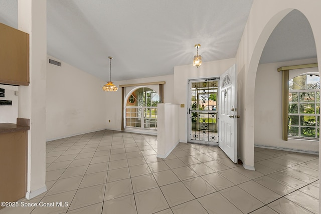 entryway with lofted ceiling, light tile patterned floors, plenty of natural light, and visible vents