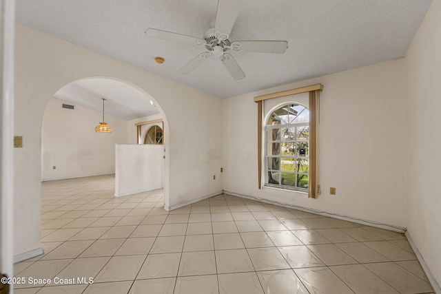 spare room featuring arched walkways, visible vents, a ceiling fan, light tile patterned flooring, and vaulted ceiling