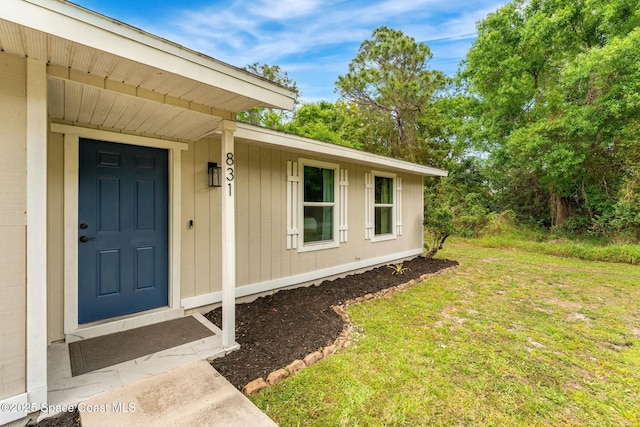 view of exterior entry featuring a lawn