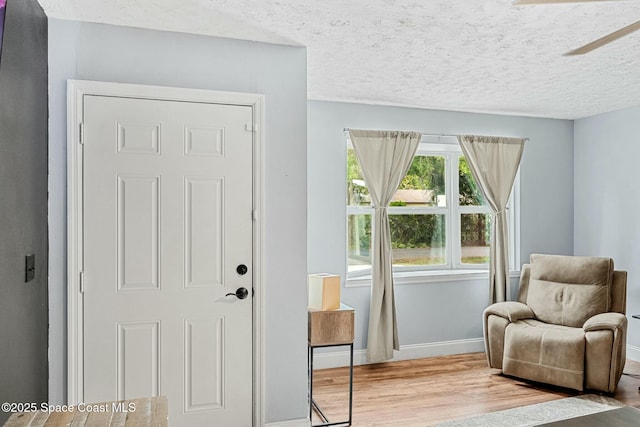 interior space with a textured ceiling, wood finished floors, and baseboards