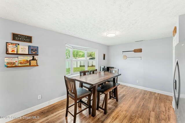 dining area featuring light wood-style floors, visible vents, and baseboards