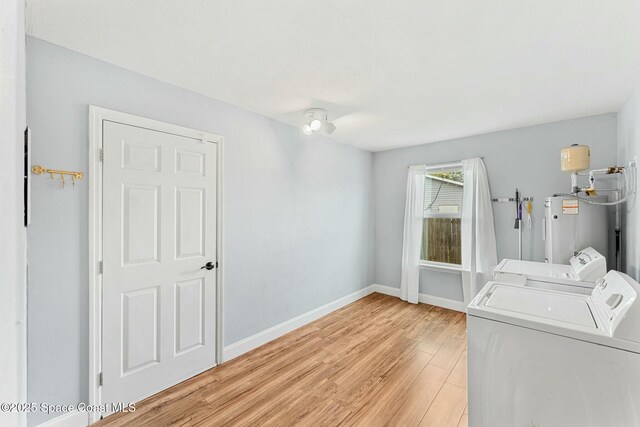 clothes washing area featuring laundry area, light wood finished floors, baseboards, independent washer and dryer, and water heater