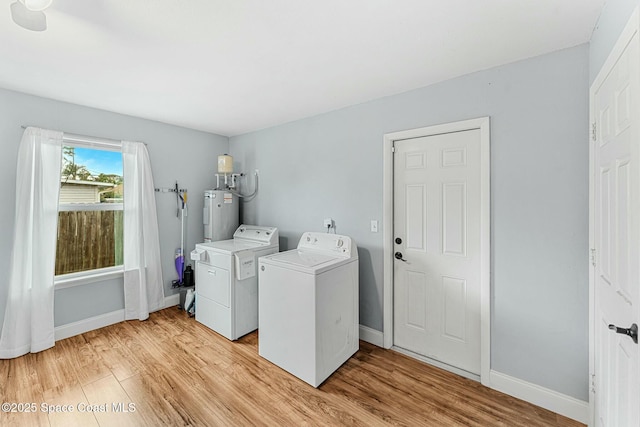 clothes washing area with electric water heater, laundry area, baseboards, light wood-style floors, and independent washer and dryer